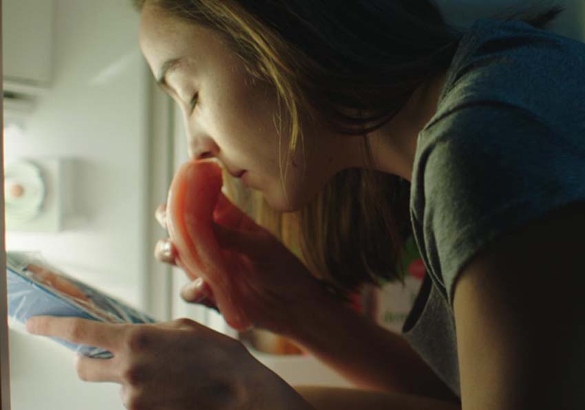 Una chica oliendo un trozo de carne